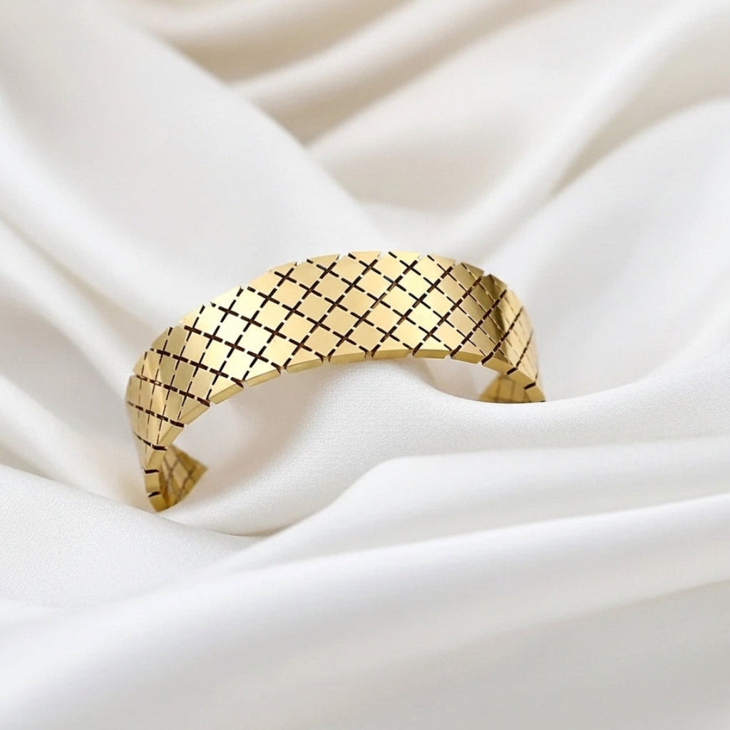 Gold bracelet with a checkered pattern on a white fabric background